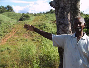 This peasant farmer’s land has a 200 meter wide cleared corridor where the two oil pipelines pass through. The pipelines have disrupted water supplies so badly that he can no longer work the farm. He has lost his fish ponds and a small mine as well as his animals and his crops. His family has moved away.